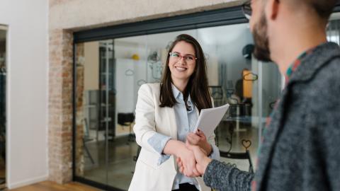 Eine junge Frau und ein Mann schütteln sich die Hände.