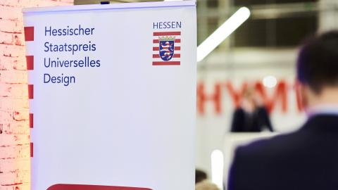 Flagge mit dem Schriftzug des Hessischen Staatspreises Universelles Design und Hessen-Wappen
