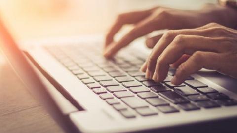 Eine PErson tippt auf die Tastatur des Laptops.  Eine Person tippt auf die Tastatur des Laptops.