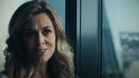 Frau steht lächelnd am Fenster