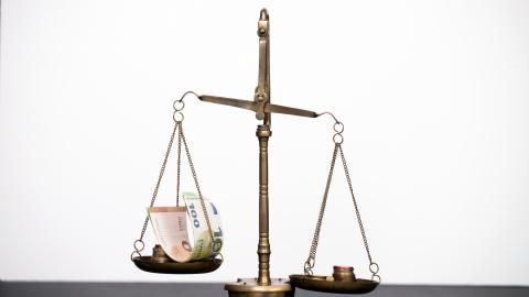 Neordnung des Kommunalen Finanzausgleichs Eine Waage mit Geldscheinen auf der linken Waagschale und Münzen auf der rechten Waagschale.