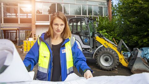 Projektleiterin Deborah Wagner sichtet vor Ort auf der Baustelle einen Bauplan. 