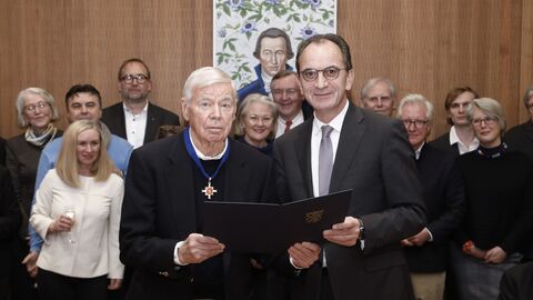  Professor Dr. Werner Meißner und Finanzminister Michael Boddenberg bei der Übergabe des verdientsordens, beide schauen in die Kamera, im Hintergrund weitere Personen.