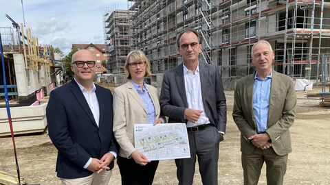 Finanzminister Boddenberg mit drei Beteiligten am Neubauprojekt Schönhof-Viertel. Sie stehen auf der Baustelle vor einem im Bau befindlichen Gebäude.