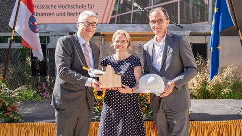 50 Jahre Rotenburg Karl Jennemann, Tanja Eichner und Michael Boddenberg übergeben einen Werkzeugkasten und Bauhelm.