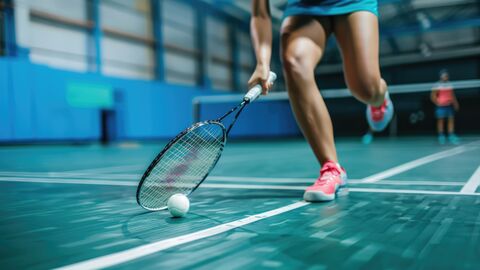 Zu sehen sind aus der Froschperspektive ein Tennisplatz in einer Halle sowie zwei Spieler beim Tennisspielen.