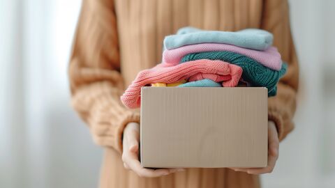 Eine Person überreicht einen Karton mit Kleidungsstücken.