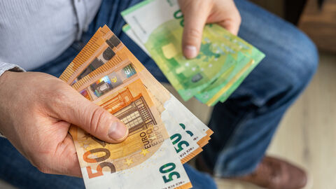 Ein Mann hält Geldscheine in seinen Händen.