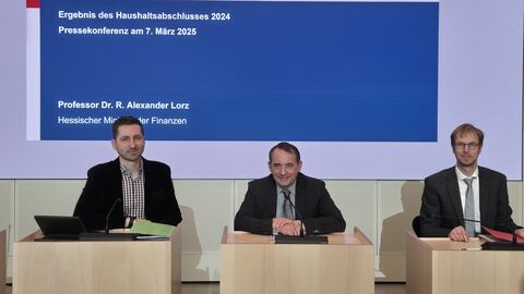 Hessens Finanzminister Professor Dr. R. Alexander Lorz (Mitte), Haushaltsdirektor Dr. Gerrit Rüdiger (rechts) und Pressesprecher Ralph-Nicolas Pietzonka (links) bei der Pressekonferenz zum Haushaltsabschluss 2024.