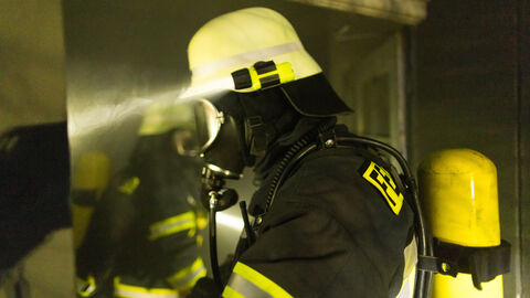 Mitglied der Feuerwehr beim Einsatz im Dunkeln mit einer Helmlampe.