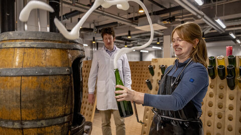 Schaum aufwirbeln Eine Studierende steht mir einer Flasche in der Hand und wirbelt Schaum auf.