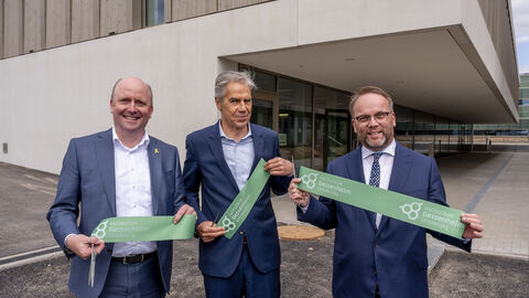 Eröffnung des GTZ Drei Personen stehen mit Teilen des durchnittenen Bandes in Händen vor dem Gebäude.