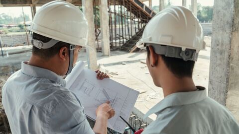 Zwei Ingenieure diskutieren auf einer Baustelle einen Bauplan. 