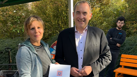 Finanzminister Lorz (rechts) überreicht den Lottobescheid über 4000 Euro an die Bürgerinitiative „Klarenthal lebt Demokratie“. 