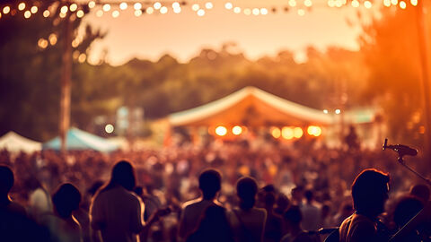 Open Air-Konzert  Zu sehen ist ein Open Air Konzert am Abend aus der Perspektive des Publikums.