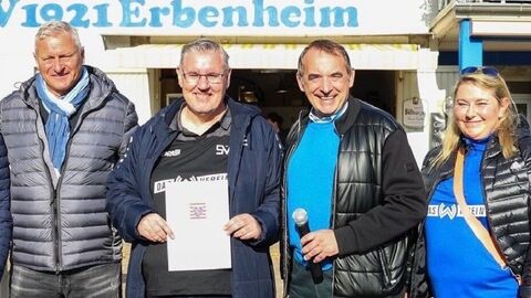 Vier Personen stehen nebeneinander - einer der Männer hält einen Förderbescheid in den Händen.