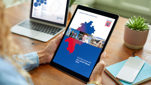 Eine Person hält ein Tablet, auf dem das Cover des Beteiligungsberichts 2024 zu sehen ist.