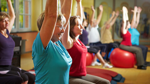 Eine Gruppe macht Gymnastikübungen auf Gummisitzbällen.