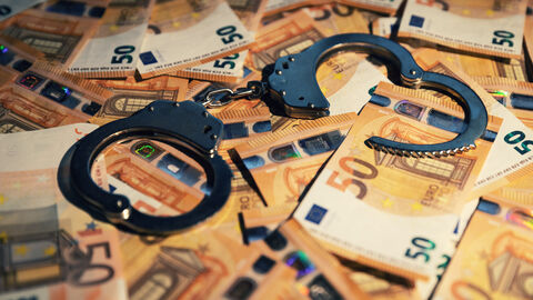 Zu sehen sind eine große Menge an 50 Euro-Scheinen, auf denen Handschellen liegen.