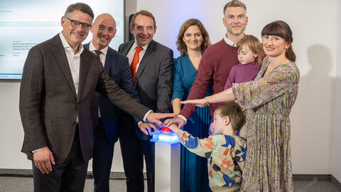 Von links nach rechts: Hessens Ministerpräsident Boris Rhein, WIBank-Sprecher Gottfried Milde, Finanzminister Professor Dr. R. Alexander Lorz, WIBank-Geschäftsführung Judith Mandel und die Hessengeld-Empfänger-Familie, Tobias und Isabel Zöller mit ihren Kindern beim Antragsstart für das Hessengeld am 19. September 2024.  Sechs Erwachsende und zwei Kinder stehen in einem Halbkreis und strecken jeweils einen Arm in die Mitte.